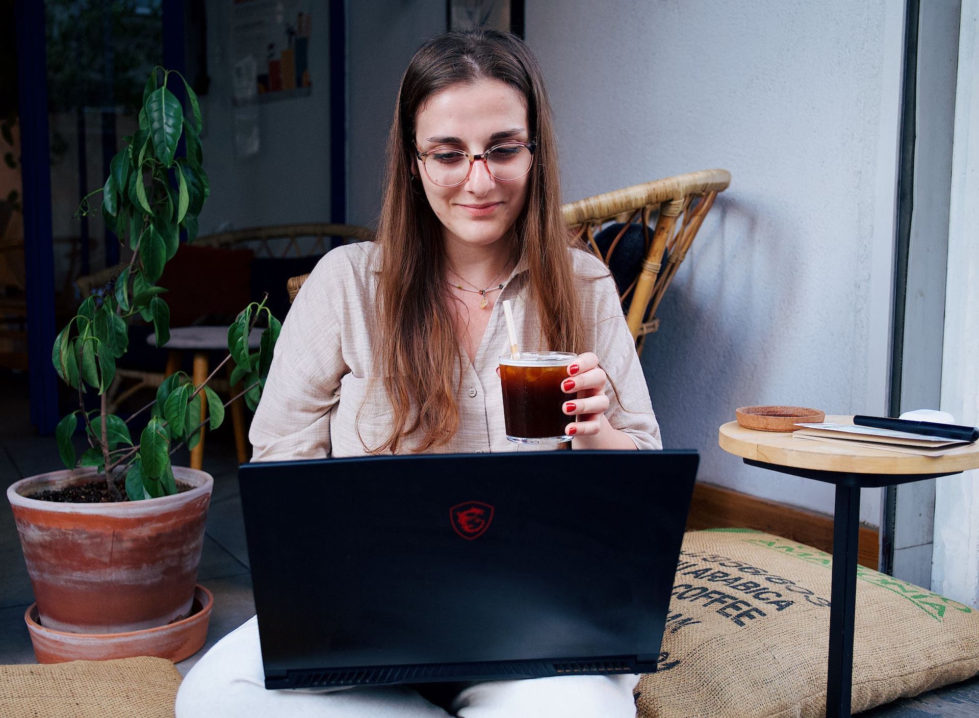 young woman sitting at computer with drink